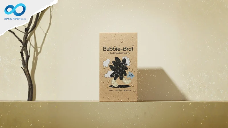 กล่องกระดาษคราฟท์ Bubble-Brot ตั้งบนฉากสีเบจ มีหยดน้ำกระจาย