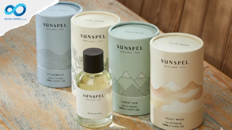กล่องกระบอกกระดาษโทนพาสเทลแบรนด์ SUNSPEL วางคู่ขวดน้ำหอมบนพื้นไม้