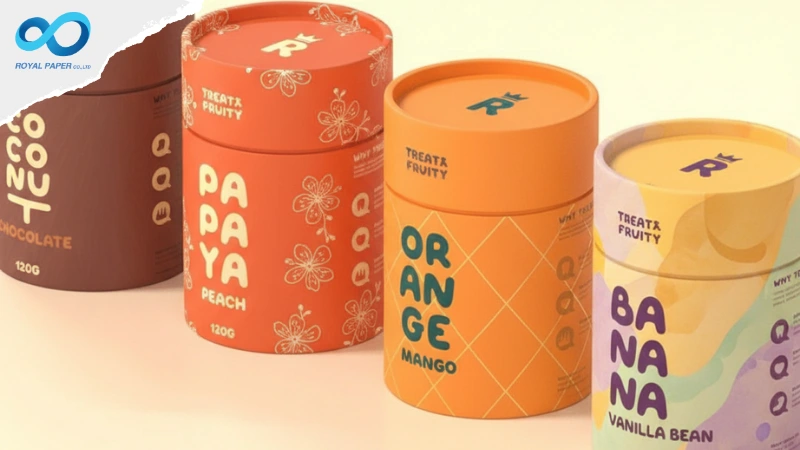 กระบอกบรรจุภัณฑ์สีสันสดใสหลายรสชาติ วางเรียง—from cocoa ถึง banana—ตัวอักษรใหญ่เต็มฝาและตัวกระบอก