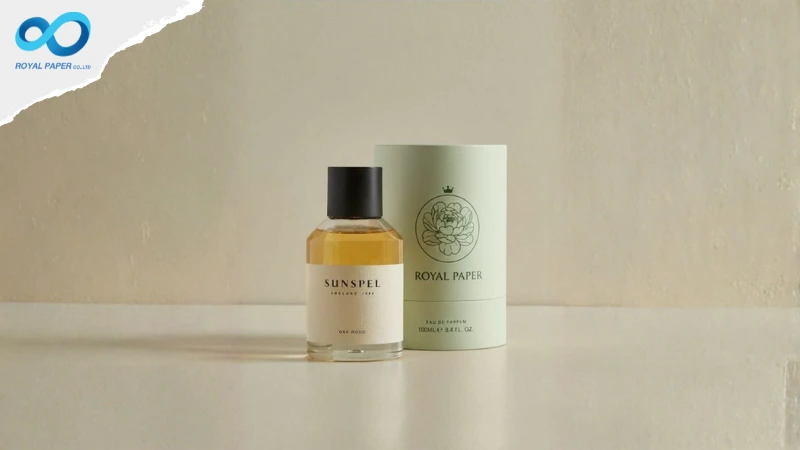 ขวดน้ำหอมวางคู่กระบอกกระดาษสีมิ้นต์อ่อนพิมพ์โลโก้ ROYAL PAPER บนพื้นเรียบโทนอุ่น